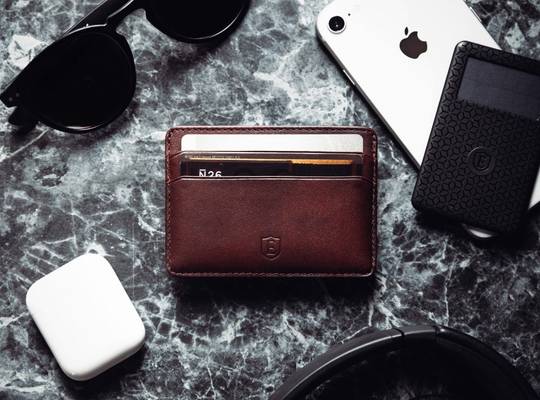 Slim leather cardholder alongside AirPods, iPhone an tracker card