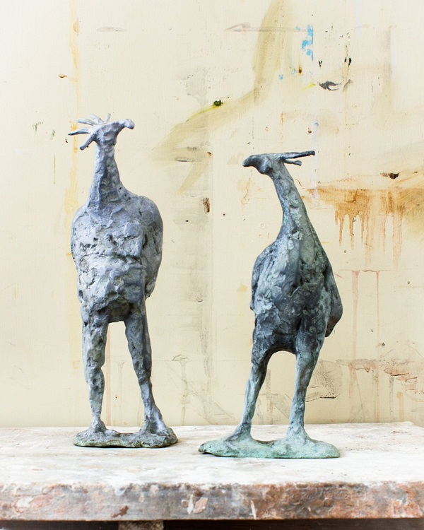 two bronze sculptures of birds with long legs