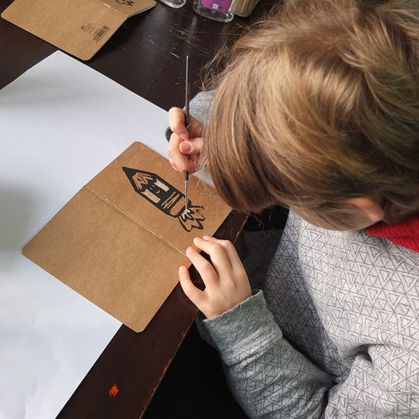a young boy adds paint to a lino cut print