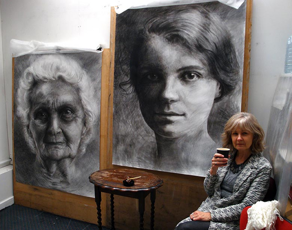 artist Ruth Wallace in her studio with artworks on the wall