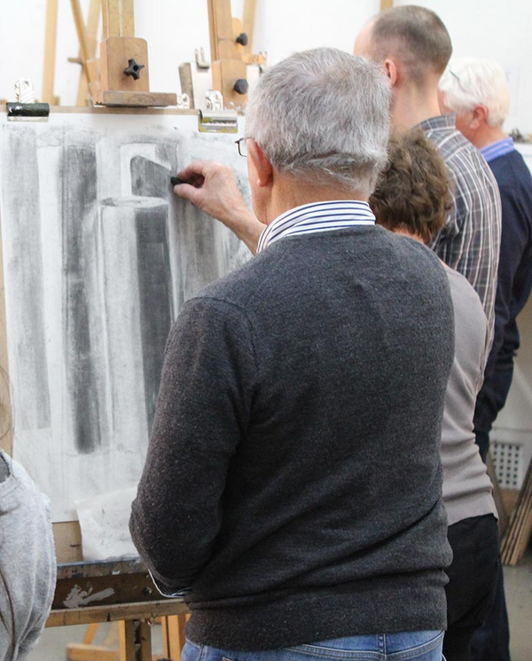 students draw with charcoal at easels