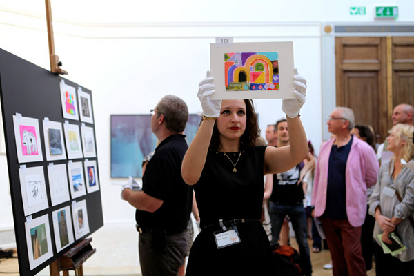 photo of lady holding up postcard during auction