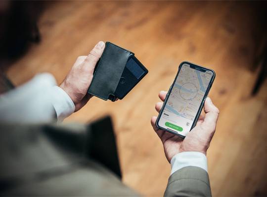 Person holding Parliament slim wallet with tracker card and smartphone with tracking app 
