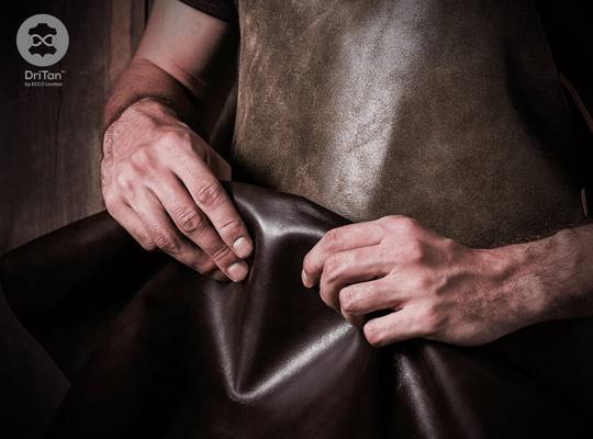 Leatherworker prepares piece of leather for manufacturing 