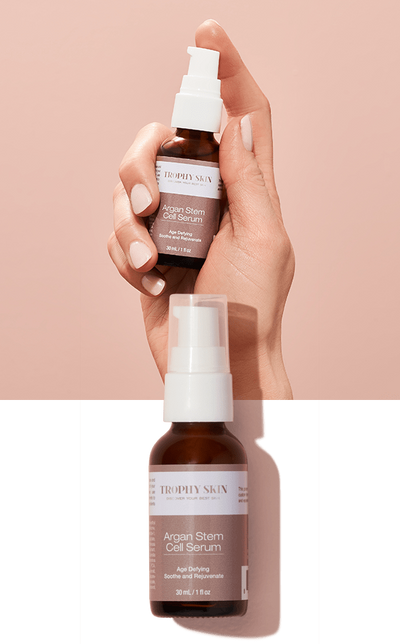 Hand holding anti-aging serum on pink background