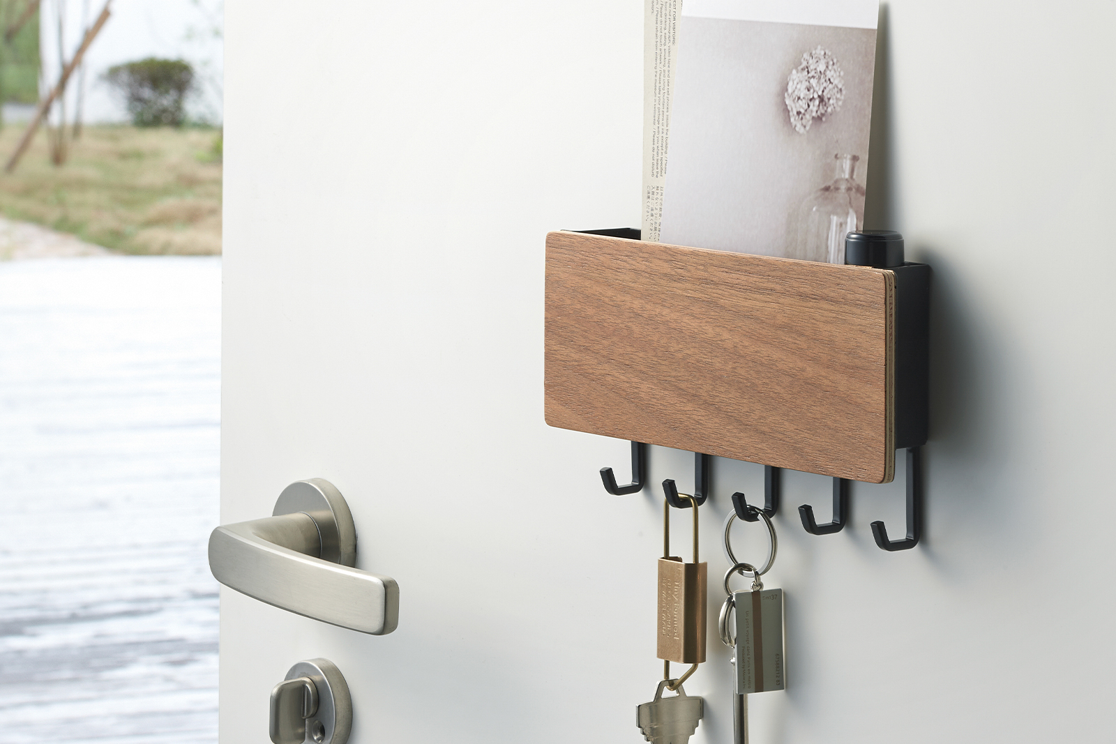 Magnetic Key Holder holding keys and paper items on door by Yamazaki Home.
