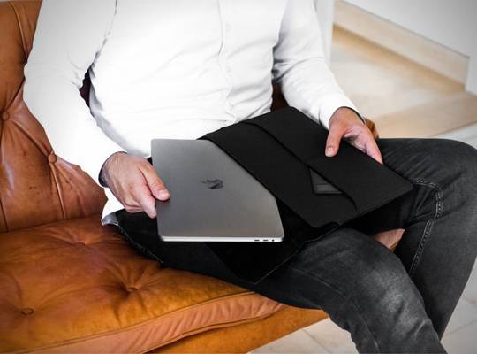 Person pulls MacBook out of leather MacBook sleeve