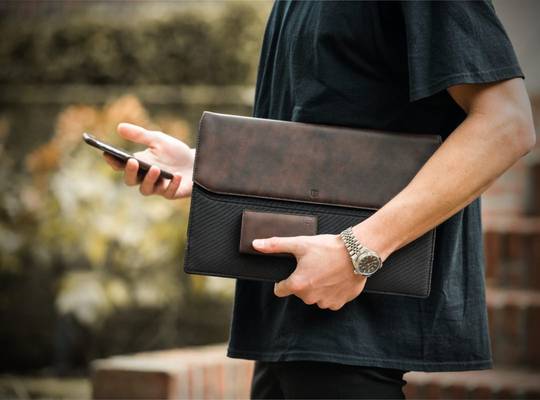 Person holds leather laptop sleeve and smart leather wallet