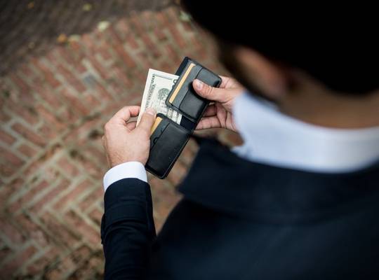 Person removing cash from premium bifold leather wallet