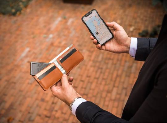 Classic leather bifold wallet with tracker card being tracked on smartphone app
