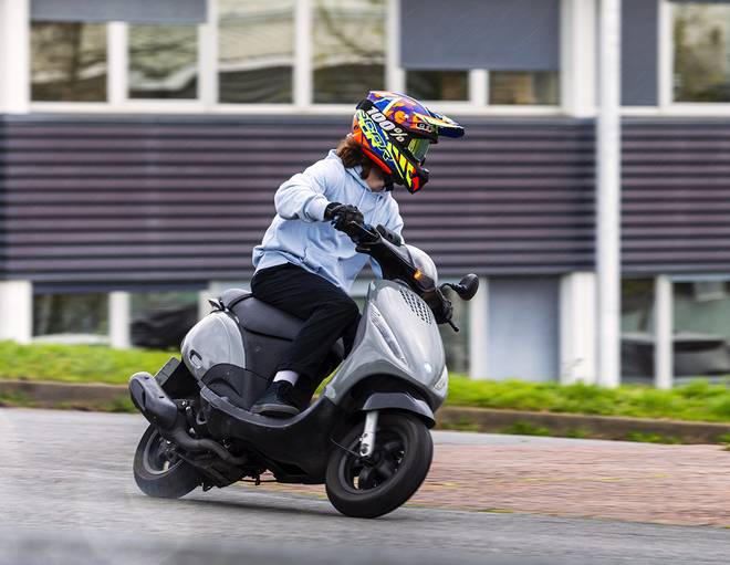 Une personne conduit un scooter 2 temps sur route