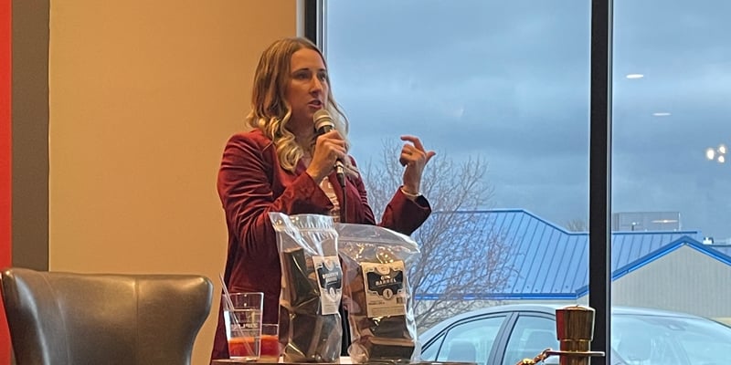 Jess Loseke, co-owner of Midwest Barrel Co., speaks at Capital Cigar Lounge in Lincoln next to table with BBQ Barrel Smoking Wood bags.