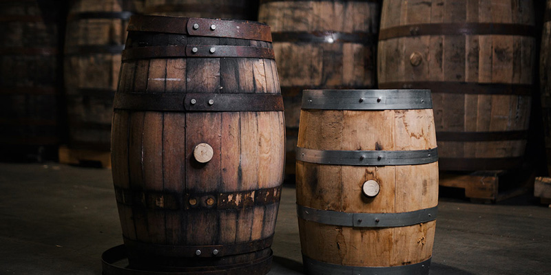 Two different sizes of whiskey barrels in a warehouse