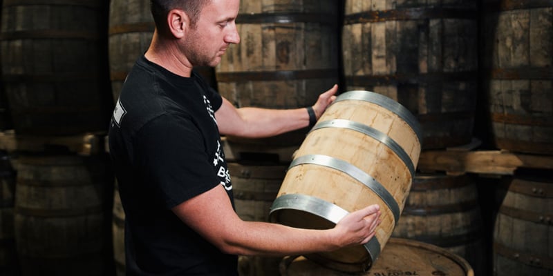 Midwest Barrel Co. Co-Owner Ben Loseke holding and inspecting a barrel