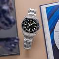 Grand Seiko SBGA231 wristwatch - a titanium cased, black dial diver atop a brown table. 