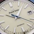 An ivory dial with silver tone markers and hands, and a blue second hand. 
