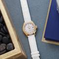 Grand Seiko wristwatch STGK004 - white dial, gold case on a white strap atop a table. 