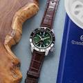 Grand Seiko SBGJ239 - green dial stainless steel wristwatch with a two-tone bezel and leather strap atop a table. 