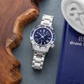Grand Seiko SBGJ237 - blue dial stainless steel wristwatch with a two-tone bezel atop a table. 