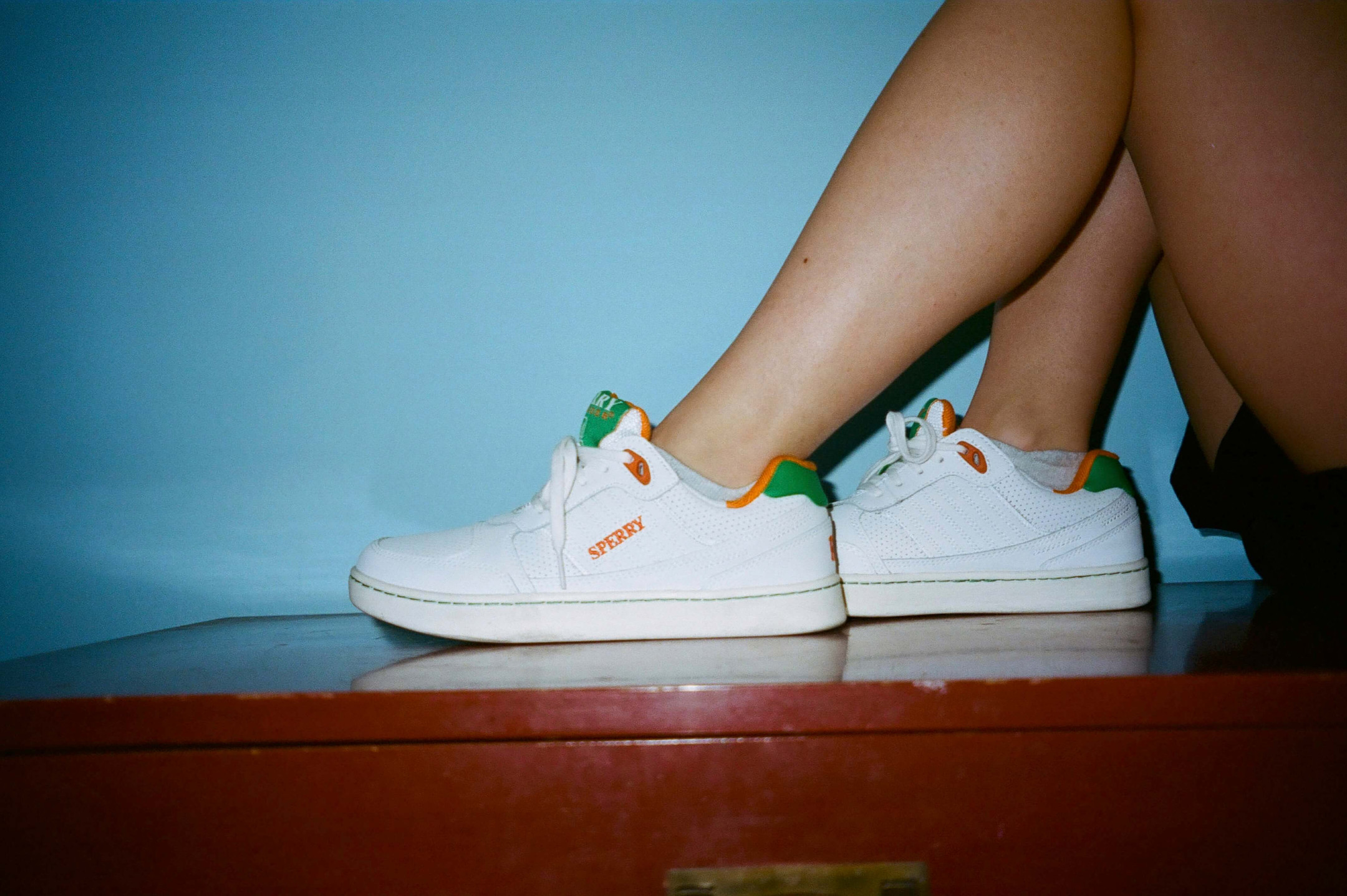 Female model wearing the Sperry x Rowing Blazers Cloud Cup Sneakers in orange and green