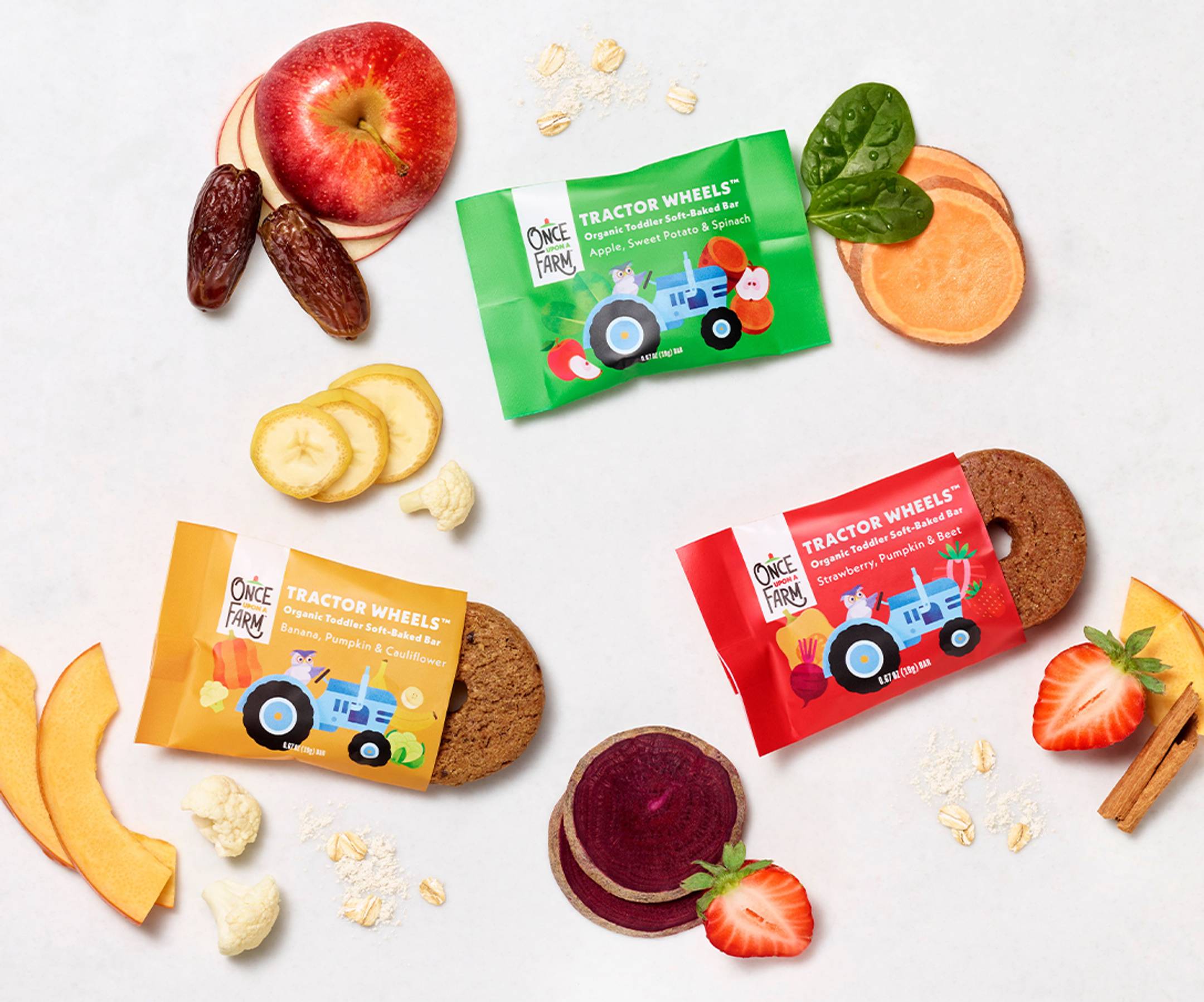 Image of our new baby & toddler pantry snack - tractor wheels toddler bars shot in a studio in 3 flavors: Strawberry, Pumpkin & Beet, Apple, Sweet Potato & Spinach, and Banana, Pumpkin & Cauliflower. With real fruit ingredients in the background. 