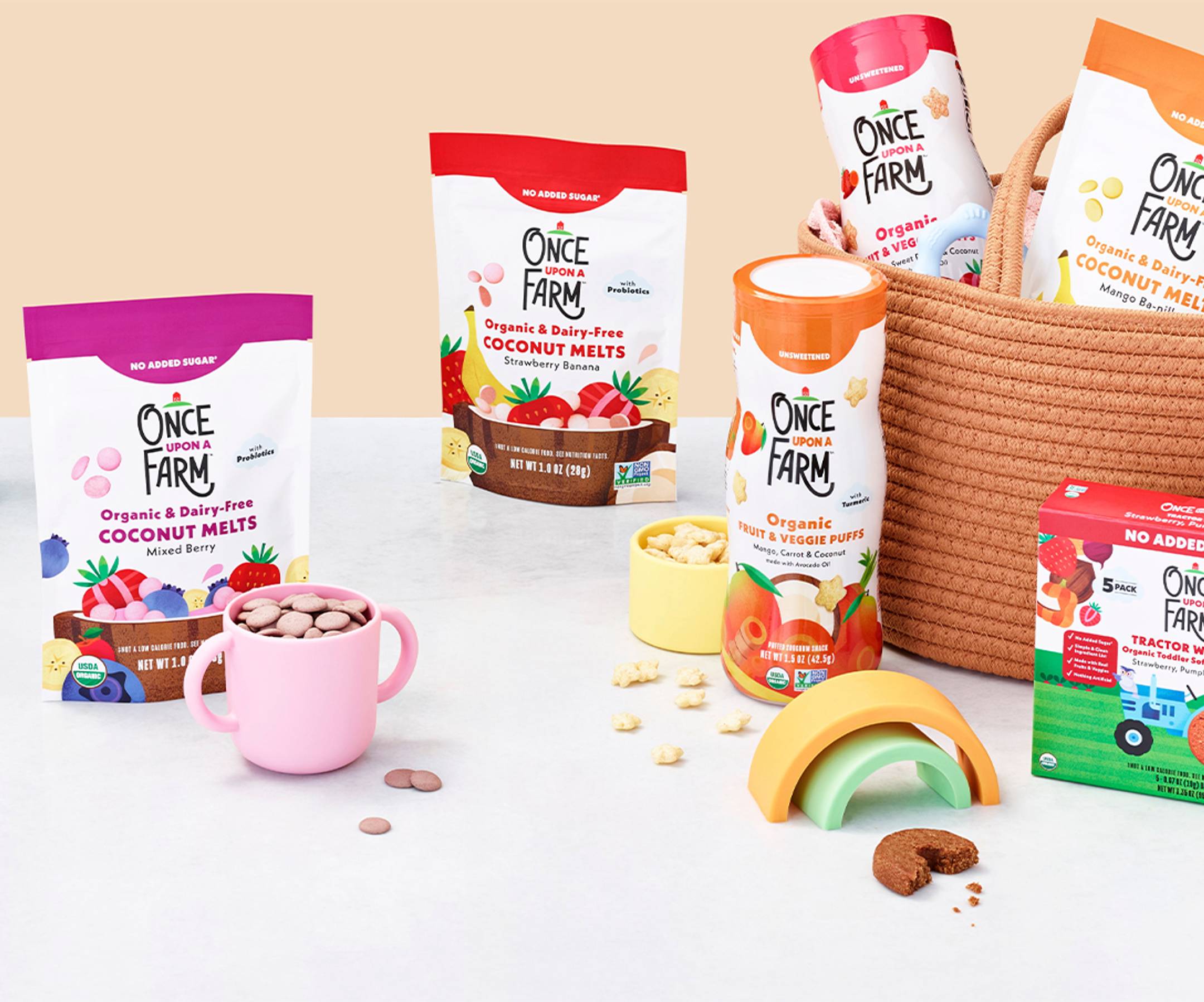 Image of our new baby & toddler pantry snacks shot in a studio. fruit & veggie puffs, coconut melts, toddler bars shaped like tractor wheels.