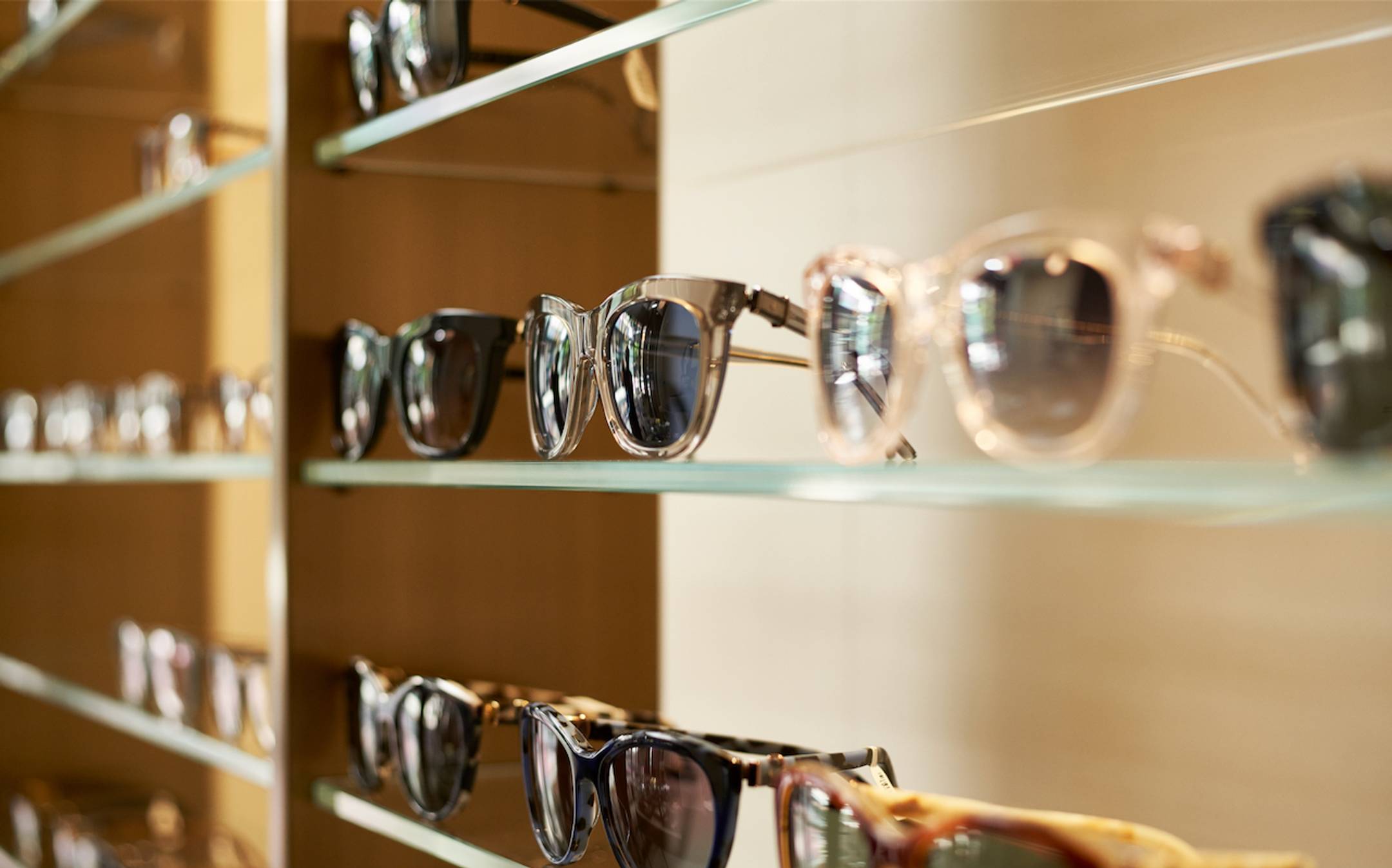 Multiple pairs of sunglasses sitting on a shelf