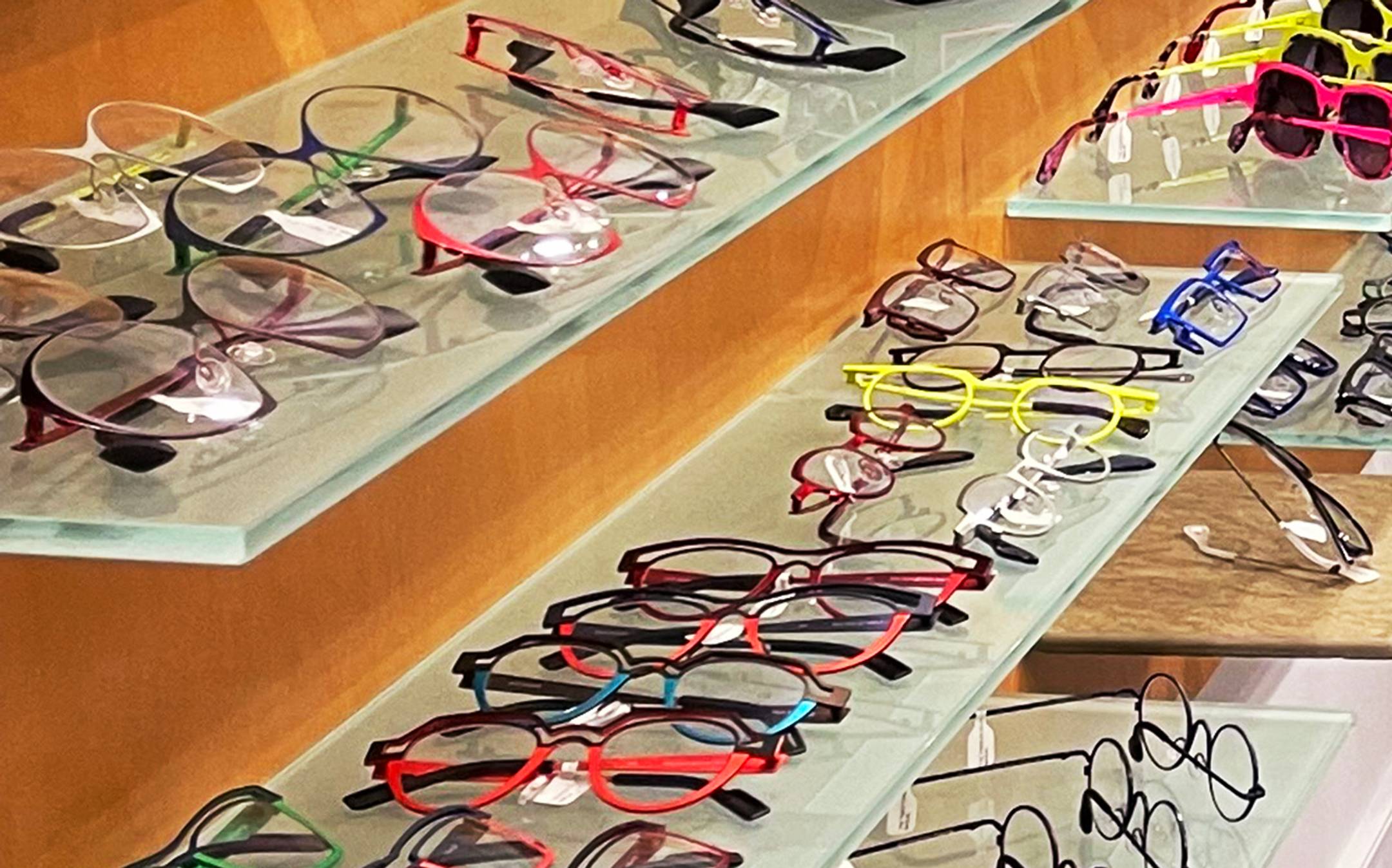 Multiple pairs of eyeglasses sitting on a shelf
