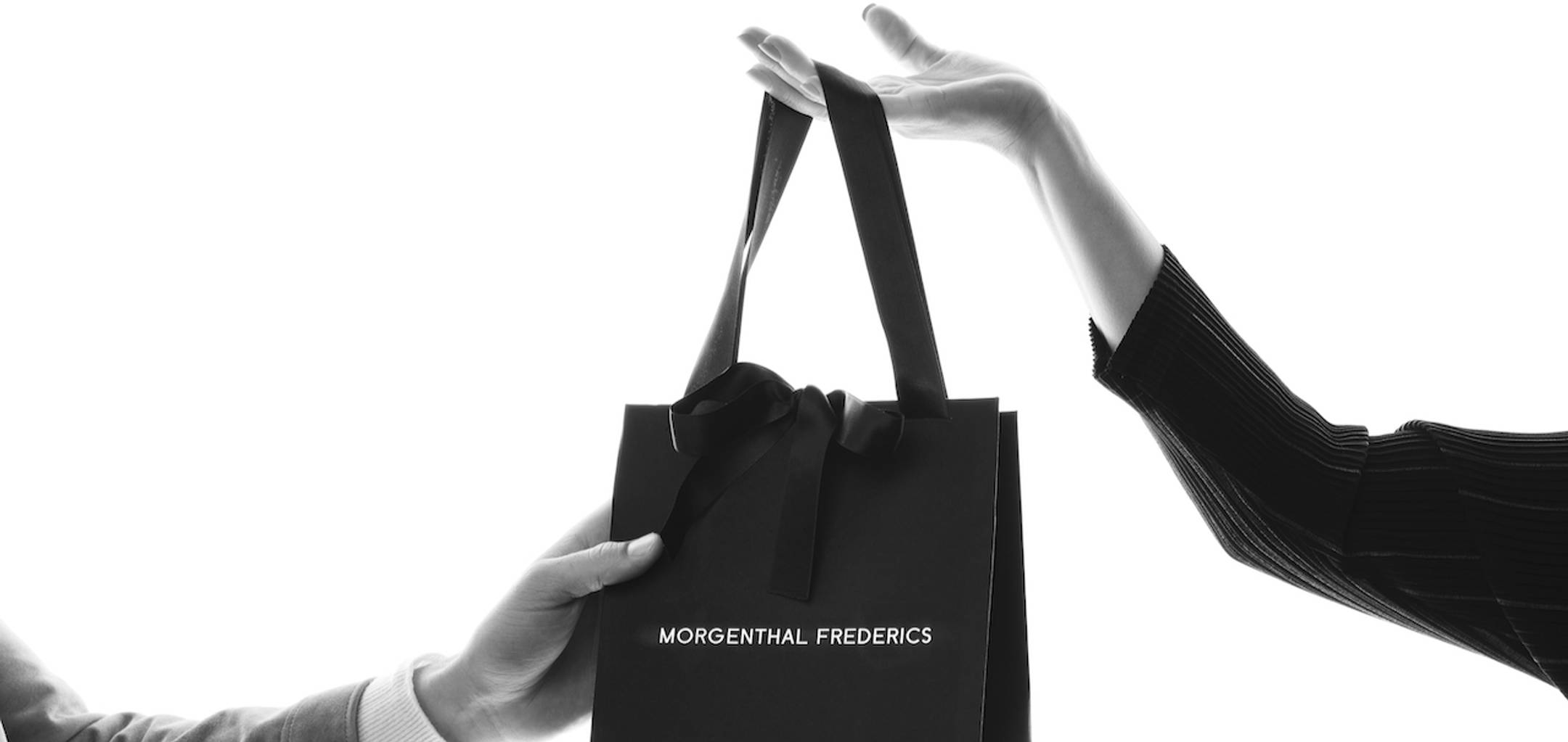 Store clerk handing a Morgenthal Frederics shopping bag to customer