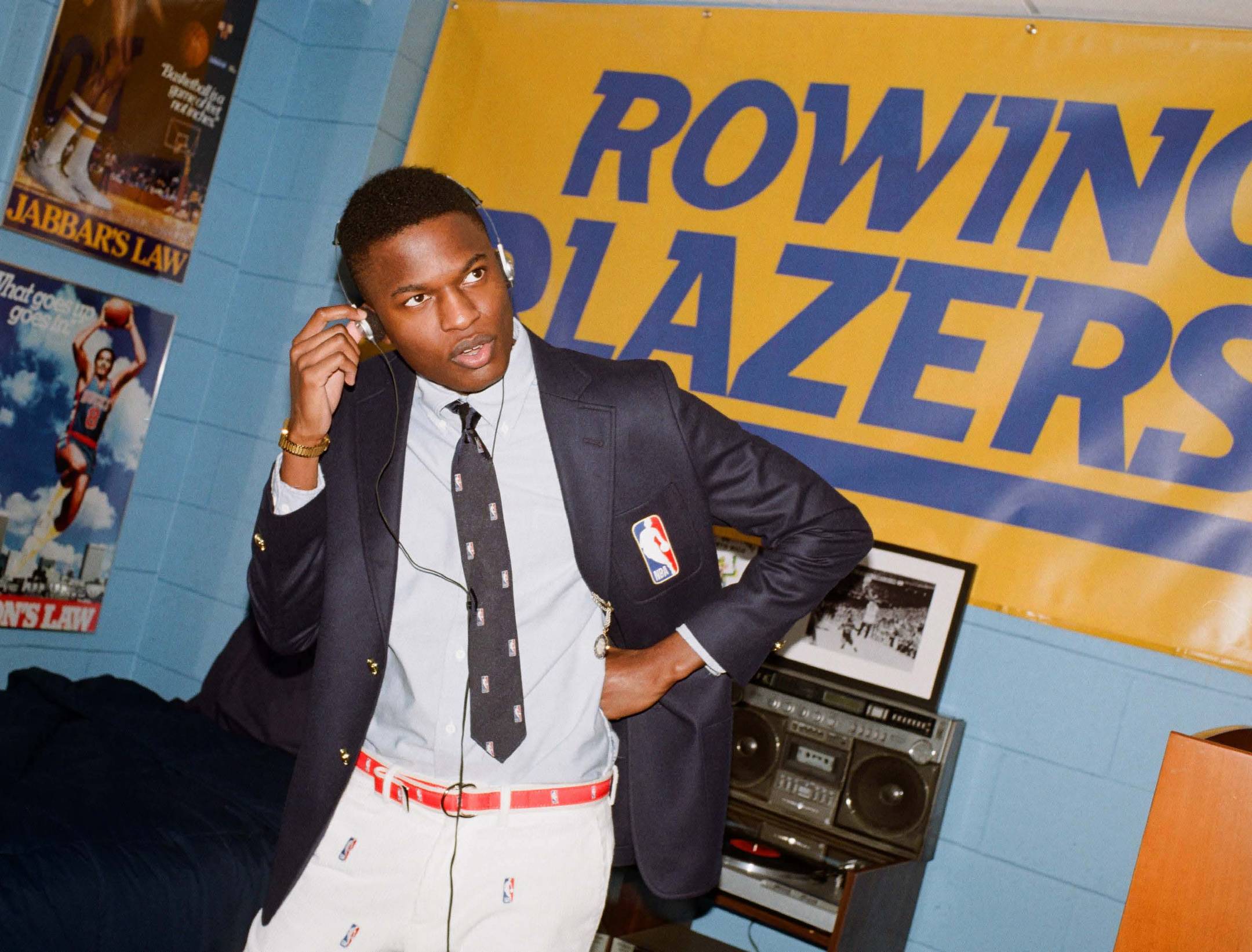 Model wearing the NBA Logo Tie, Blazer, and Belt in a recreation of one of Rowing Blazers' favorite player's freshman dorm room located at The Graduate Chapel Hill.