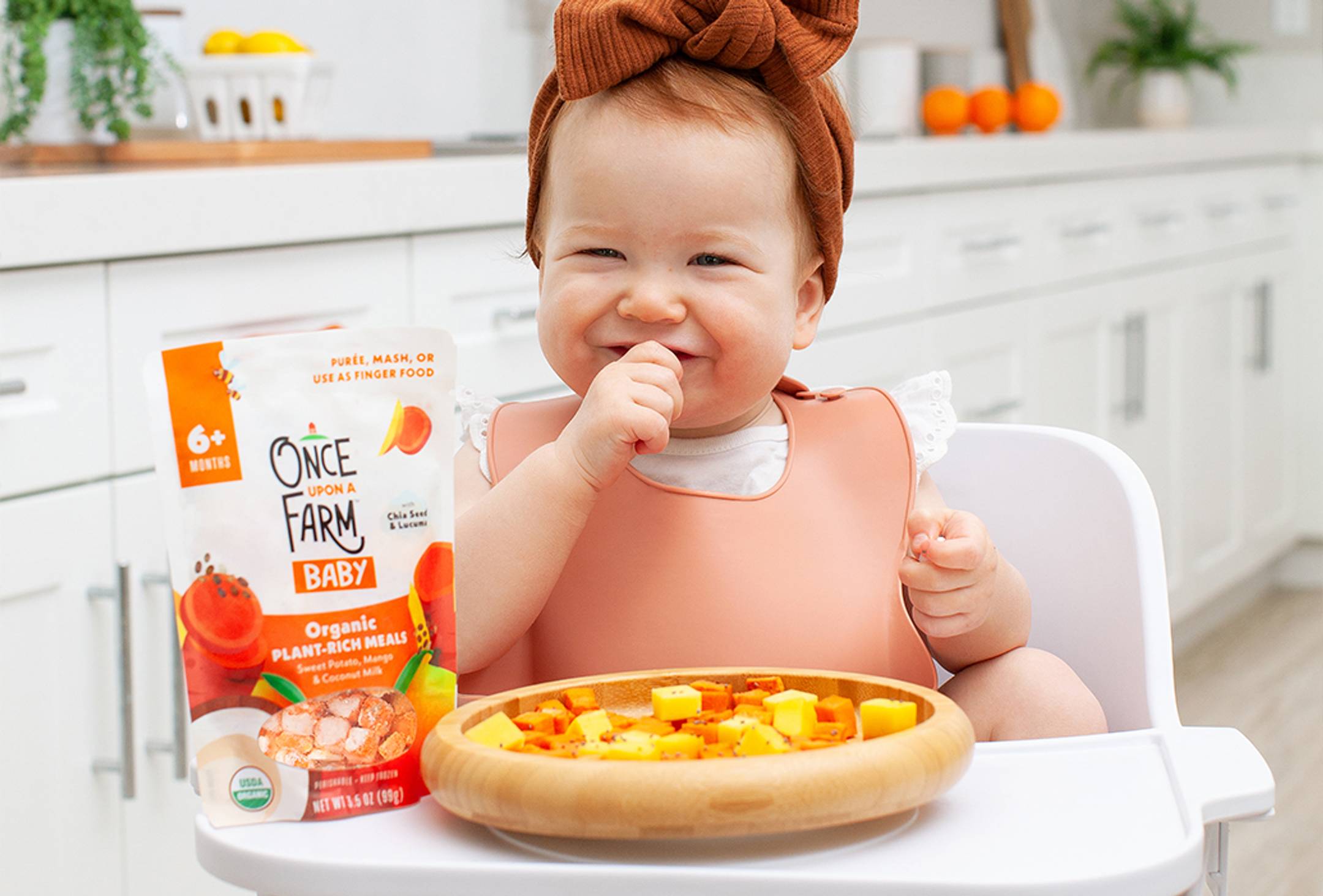 Photo of a baby eating the Sweet Potato, Mango & Coconut Milk meal as finger food.
